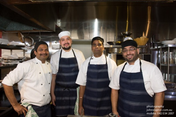 indian chefs posing in restaurant kitchen